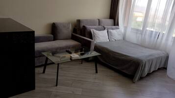 A modern hotel room with a sofa, a glass coffee table, and a bed.
