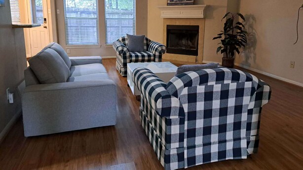 Ein Wohnzimmer mit Kamin, einer Couch, zwei Sesseln und einem Couchtisch.