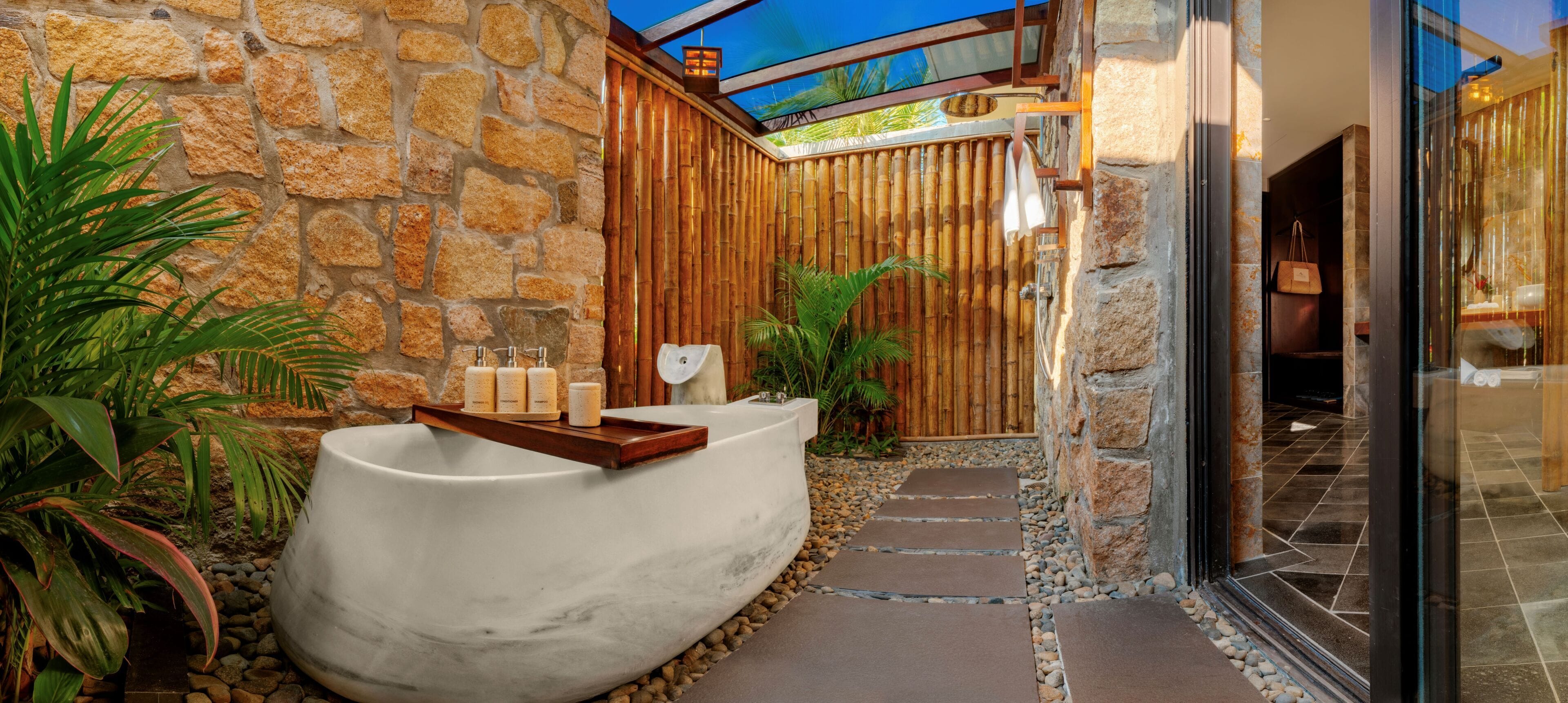 A spa area with a stone wall, a white bathtub, and a wooden deck.