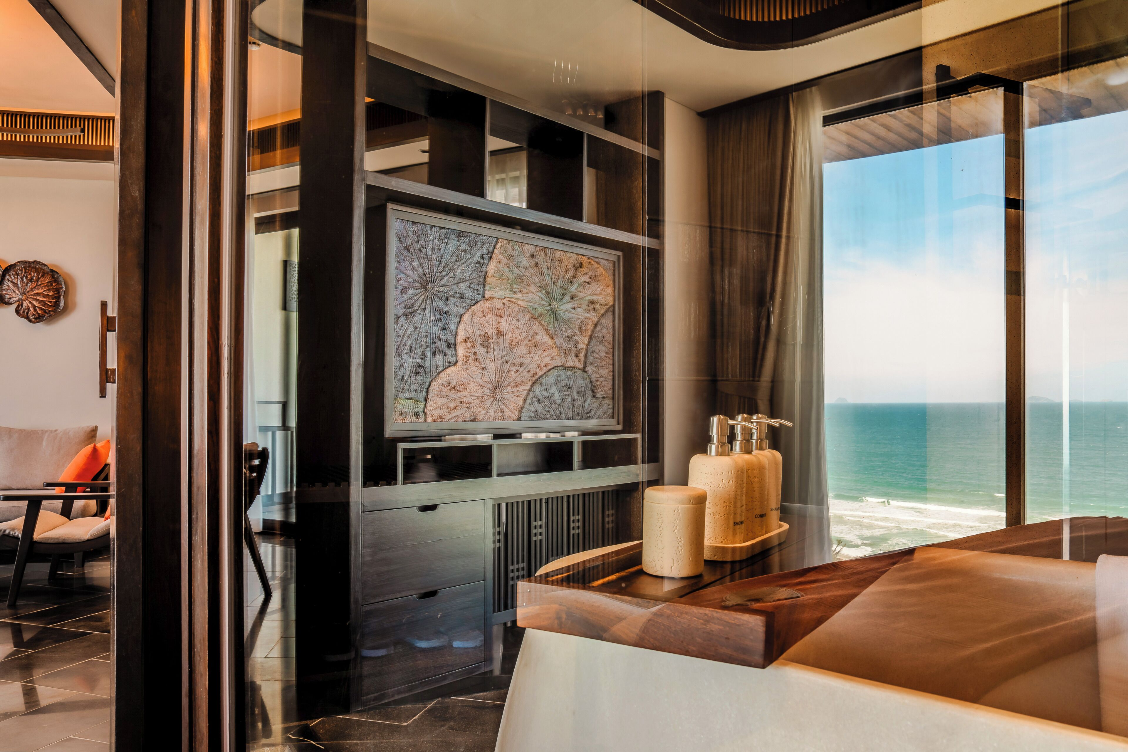 A modern interior with a large TV, a wooden coffee table, and a view of the ocean.