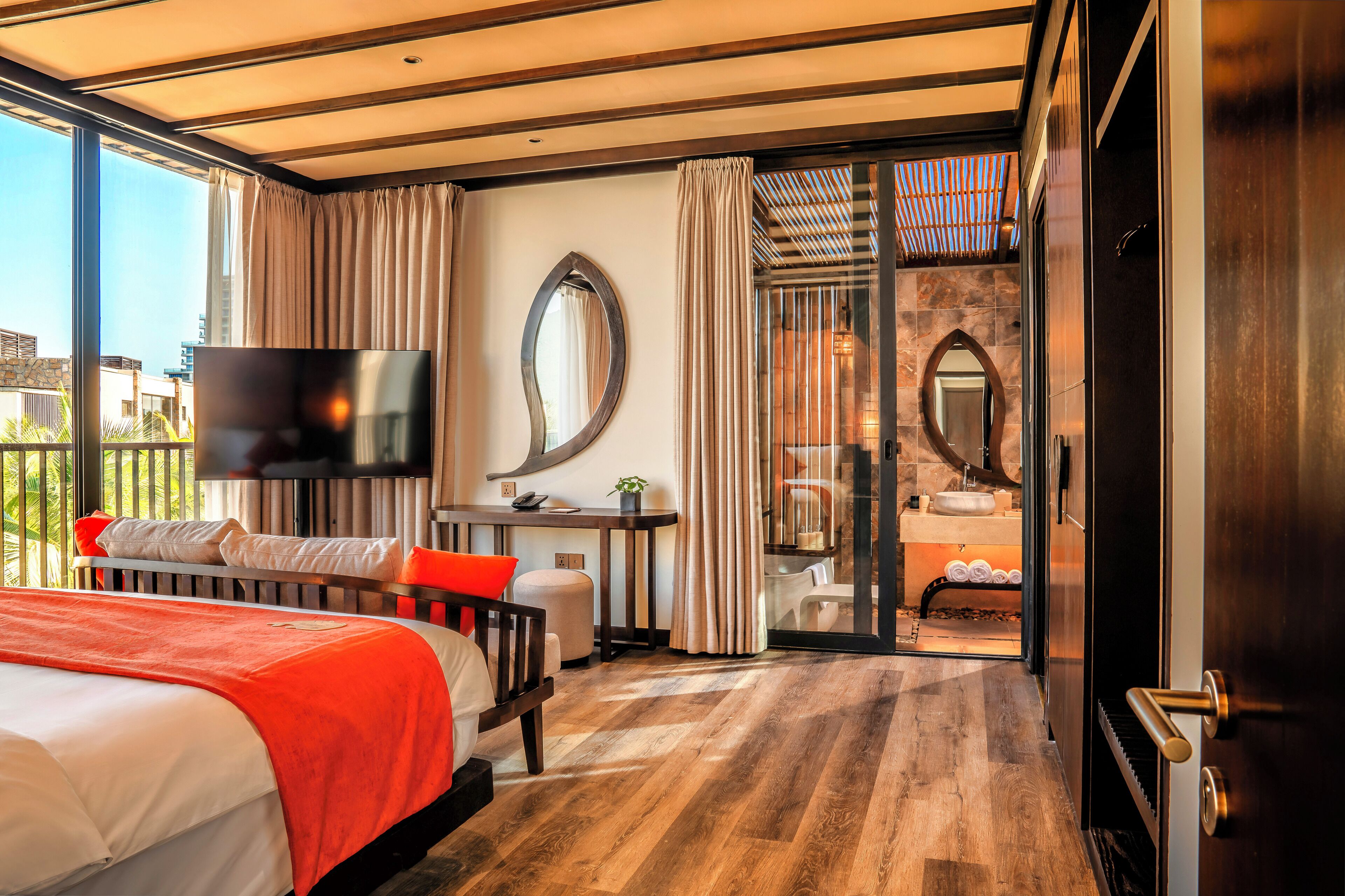 Une chambre d’hôtel moderne dotée d’un grand lit, d’un bureau, d’une télévision et d’une salle de bain avec une porte en verre.