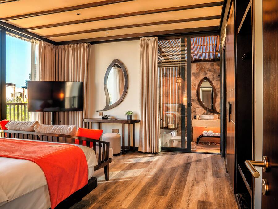 Une chambre d’hôtel moderne dotée d’un grand lit, d’un bureau, d’une télévision et d’une salle de bain avec une porte en verre.