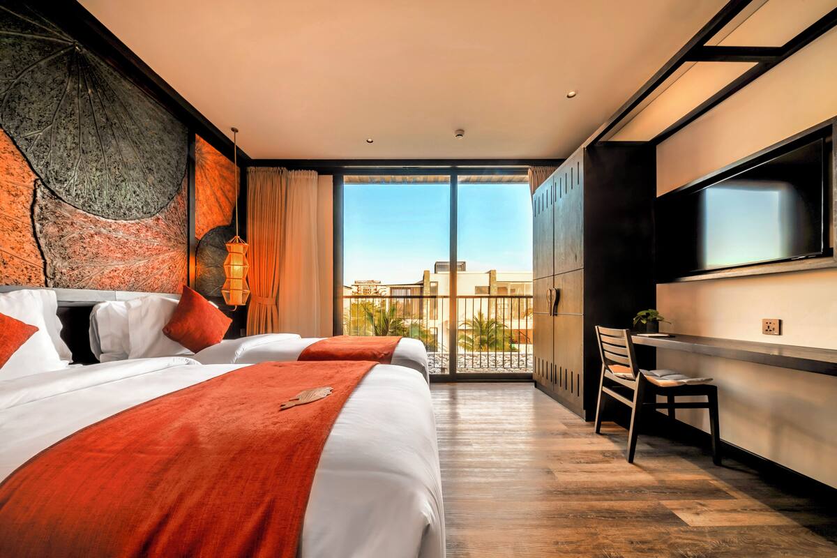 A hotel room with a large bed, a TV, a balcony with a view, and a desk.