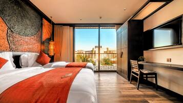 Ein Hotelzimmer mit einem großen Bett, einem Fernseher, einem Balkon mit Aussicht und einem Schreibtisch.