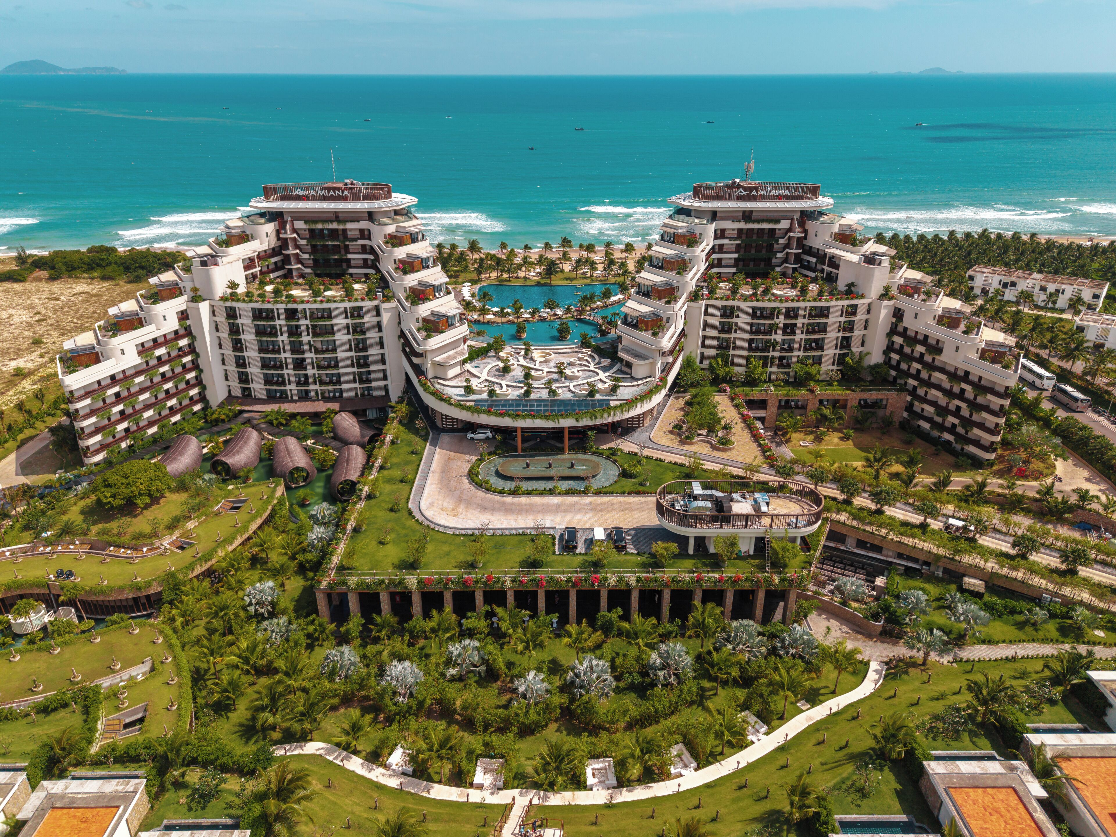 A resort with a central pool, multiple buildings, and a beach view.