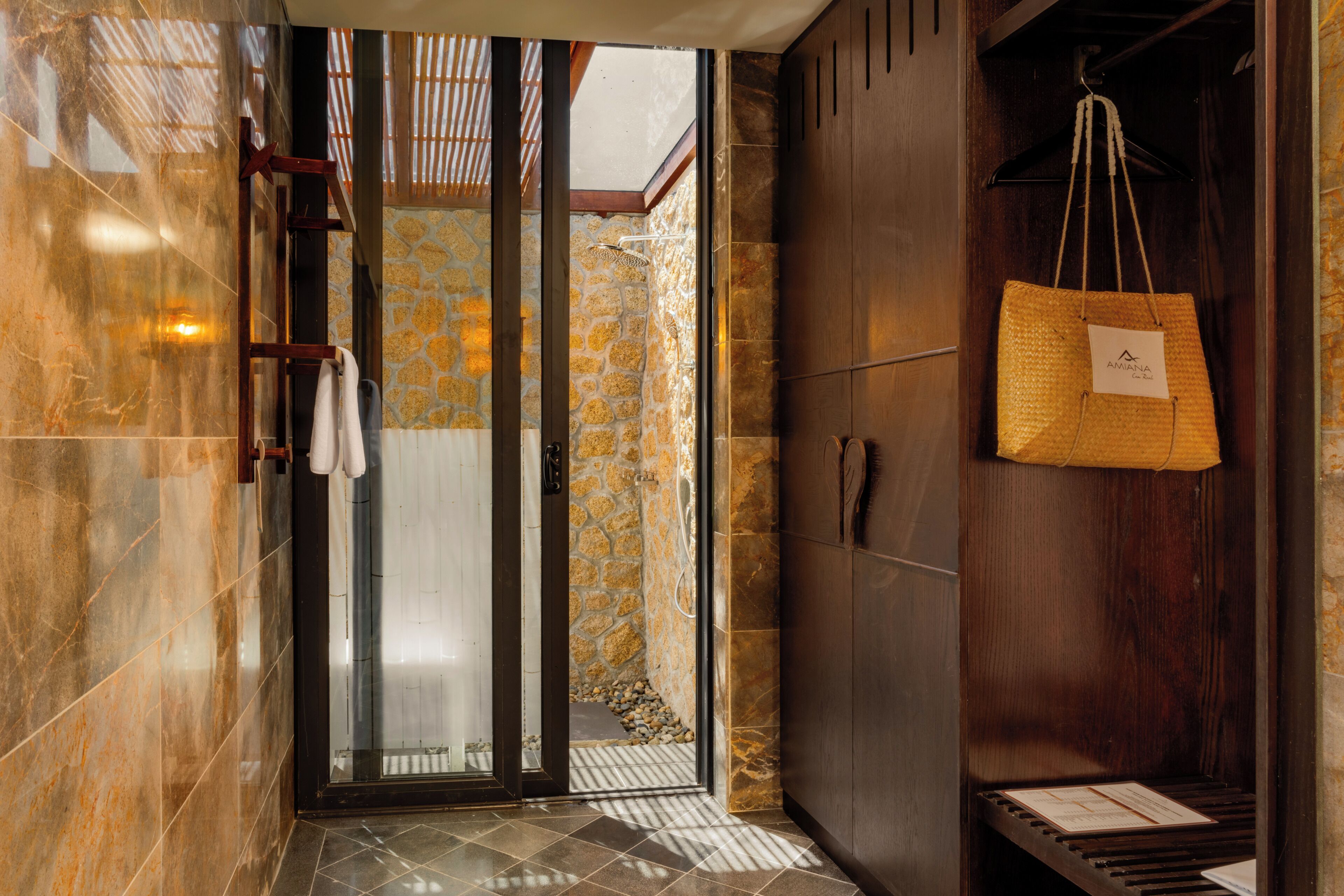 A bathroom with a stone wall, a wooden cabinet, and a hanging bag.
