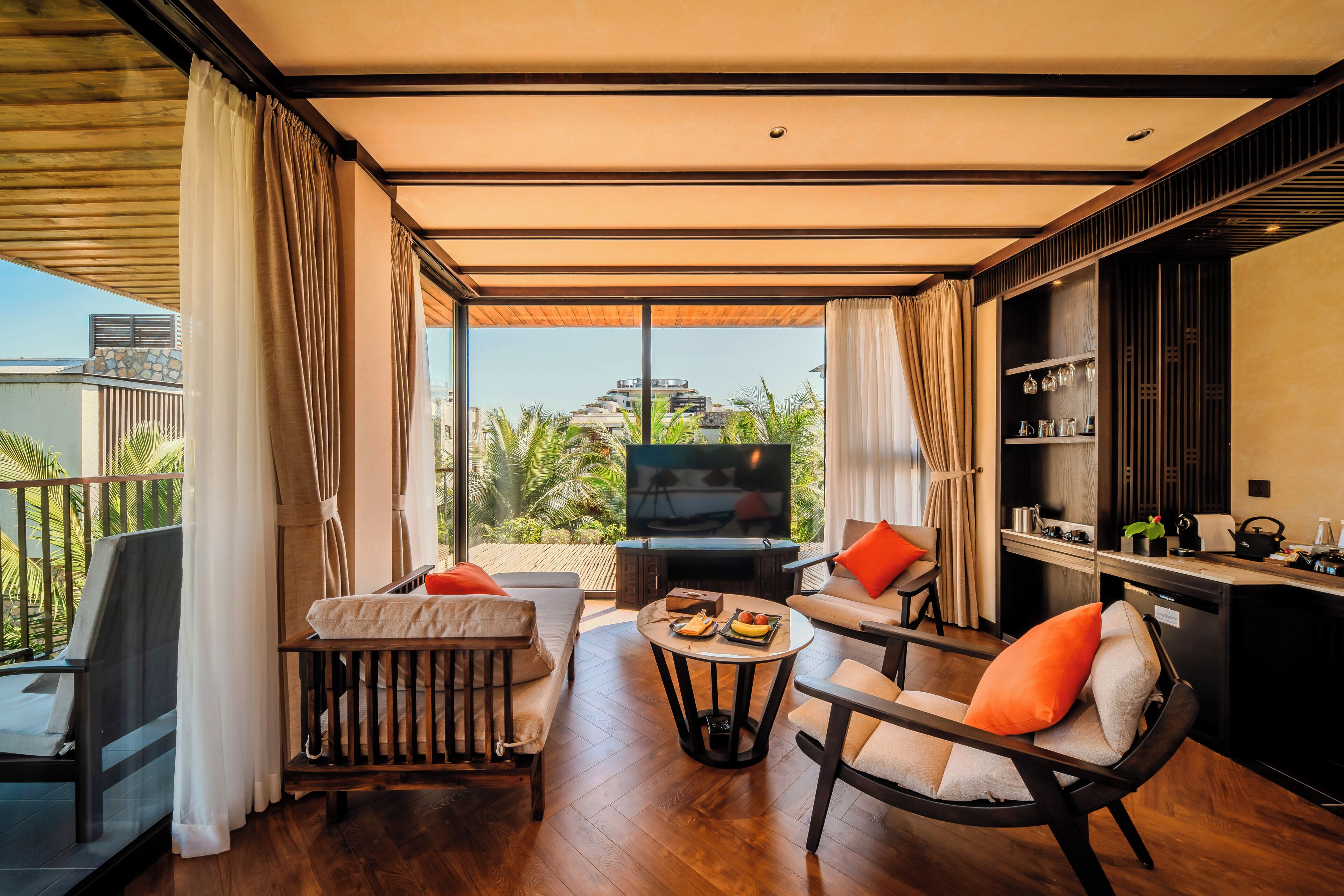 Ein modernes Wohnzimmer mit Fernseher, Sitzgelegenheiten und Blick ins Freie.