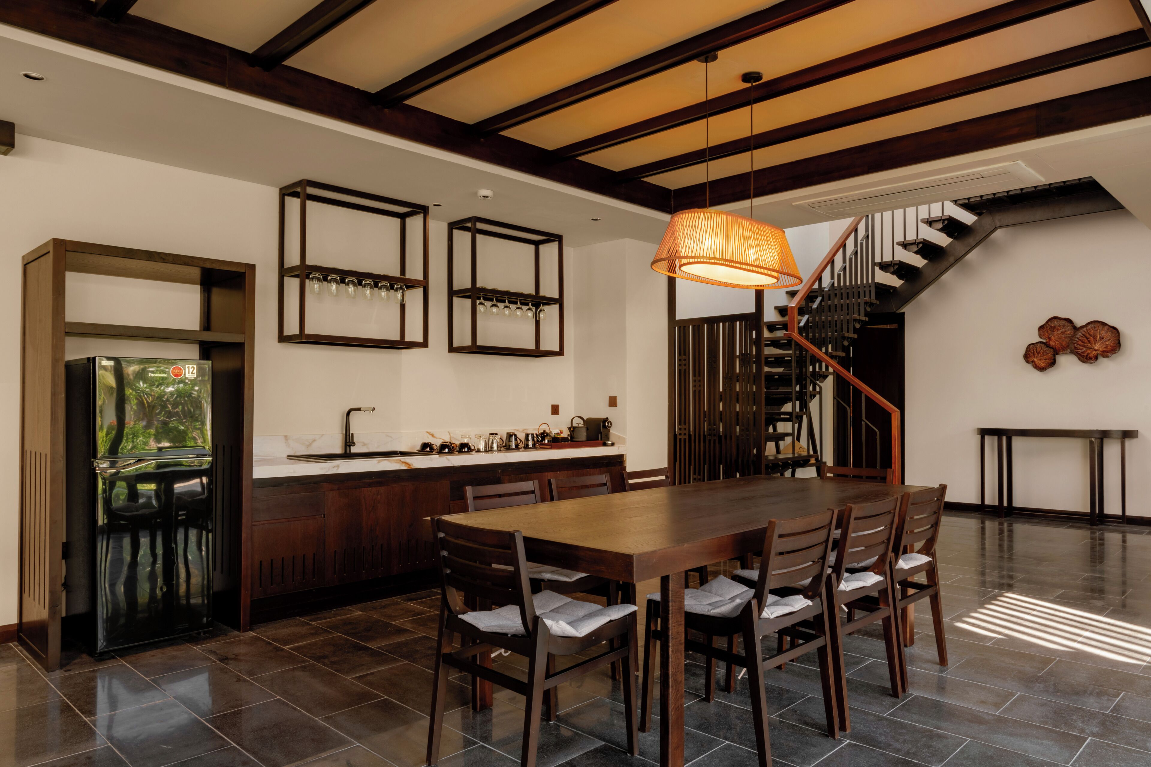 A modern kitchen with a dining area, wooden furniture, and a staircase.