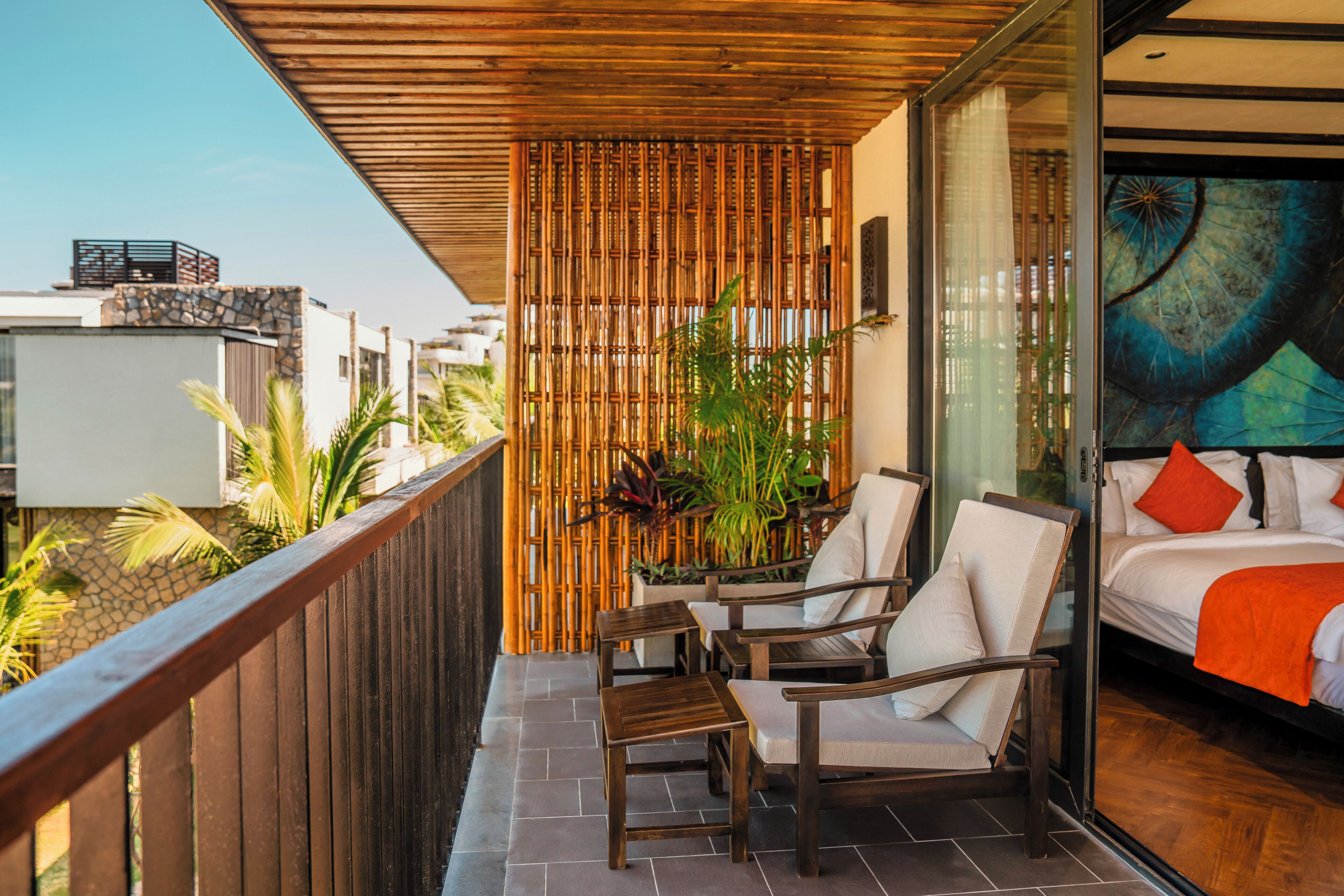 A balcony with wooden chairs and a bed with a colorful mural.