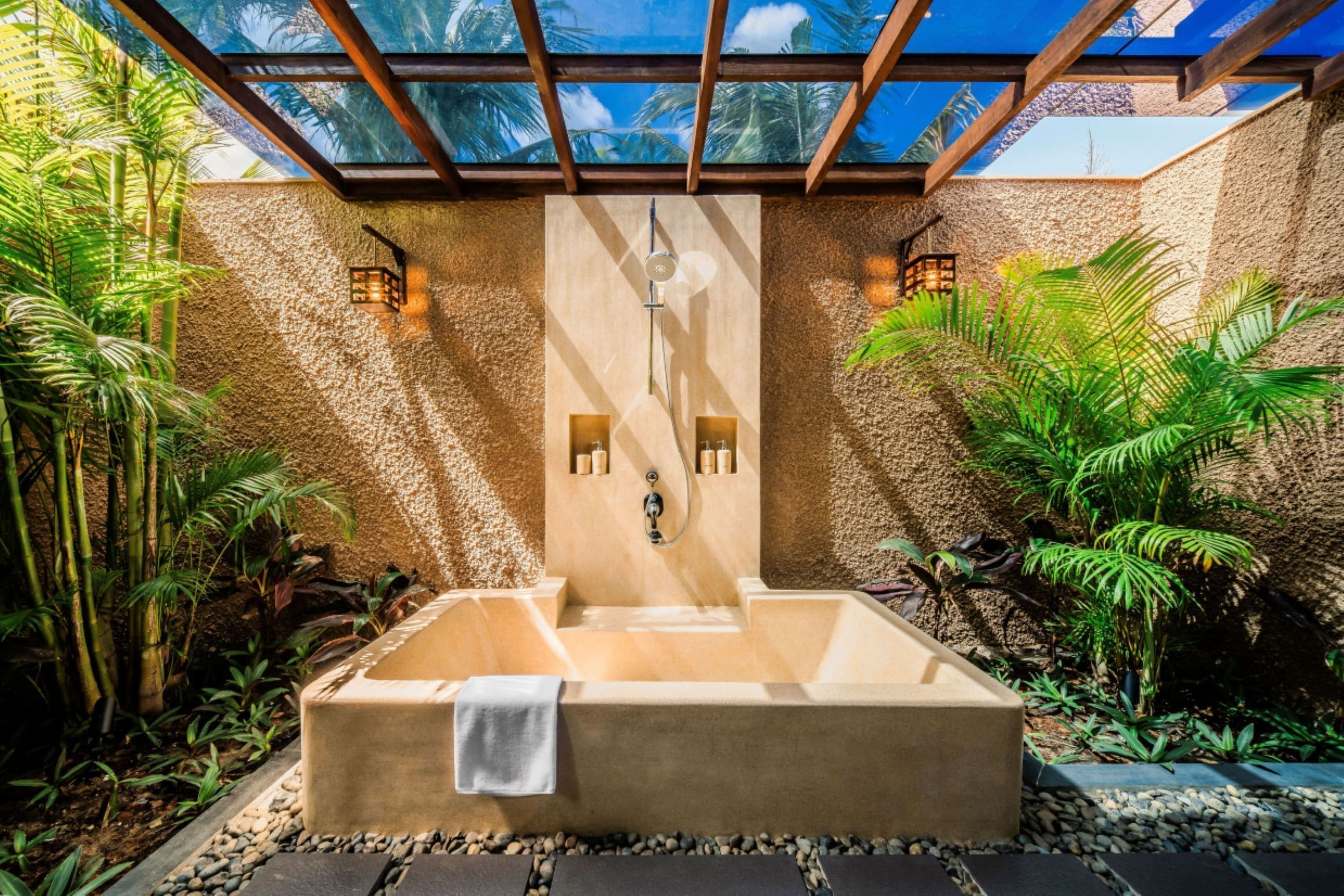 A spa area with a large bathtub, wooden walls, and tropical plants.