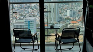 A room with a large window, two chairs, and a small table.