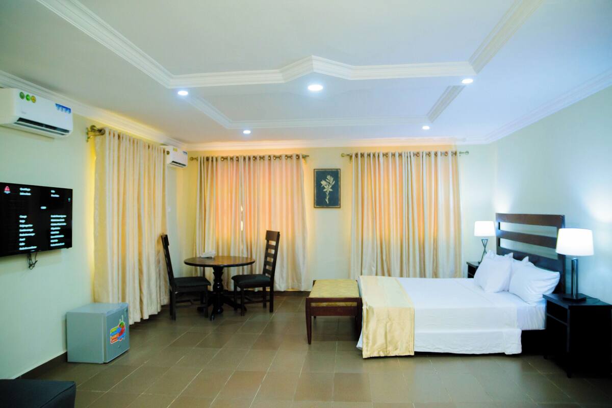 Une chambre d’hôtel équipée d’un lit, de tables de chevet, d’un bureau, de chaises, d’un appareil de climatisation et d’un téléviseur.