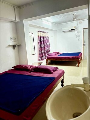 A room with two beds, a sink, and a ceiling fan. - GSR Stay Home (Puducherry)
