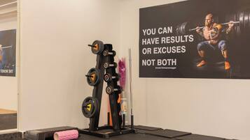 Un gimnasio con una zona de pesas y carteles de motivación en la pared.