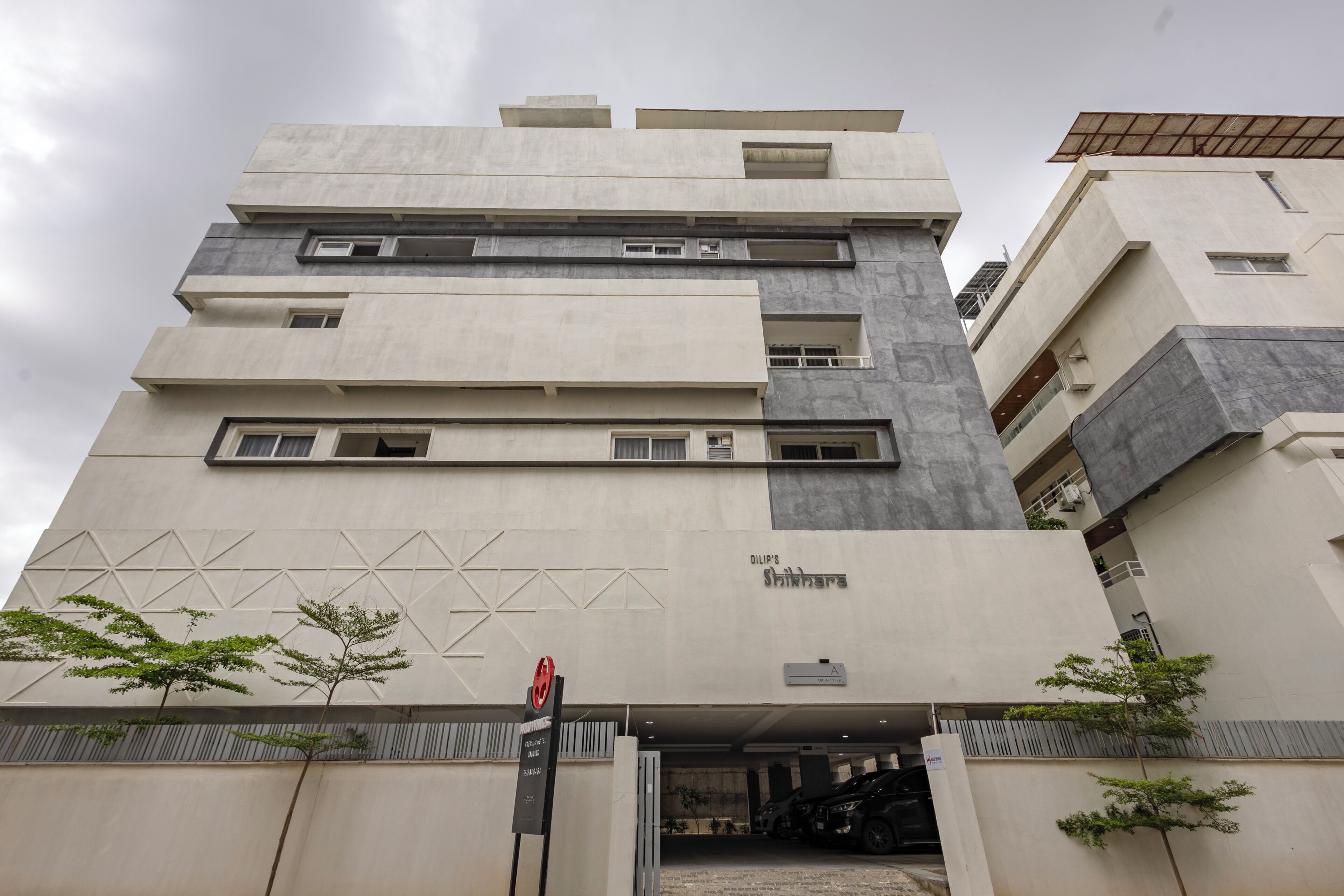 A multi-story building with a modern architectural design, featuring a prominent entrance with a gated driveway.