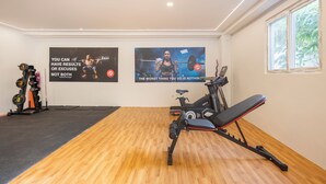 A gym with exercise equipment, wooden flooring, and motivational posters on the walls. - WILDWINGS PREMIUM HOTEL (Hyderabad)