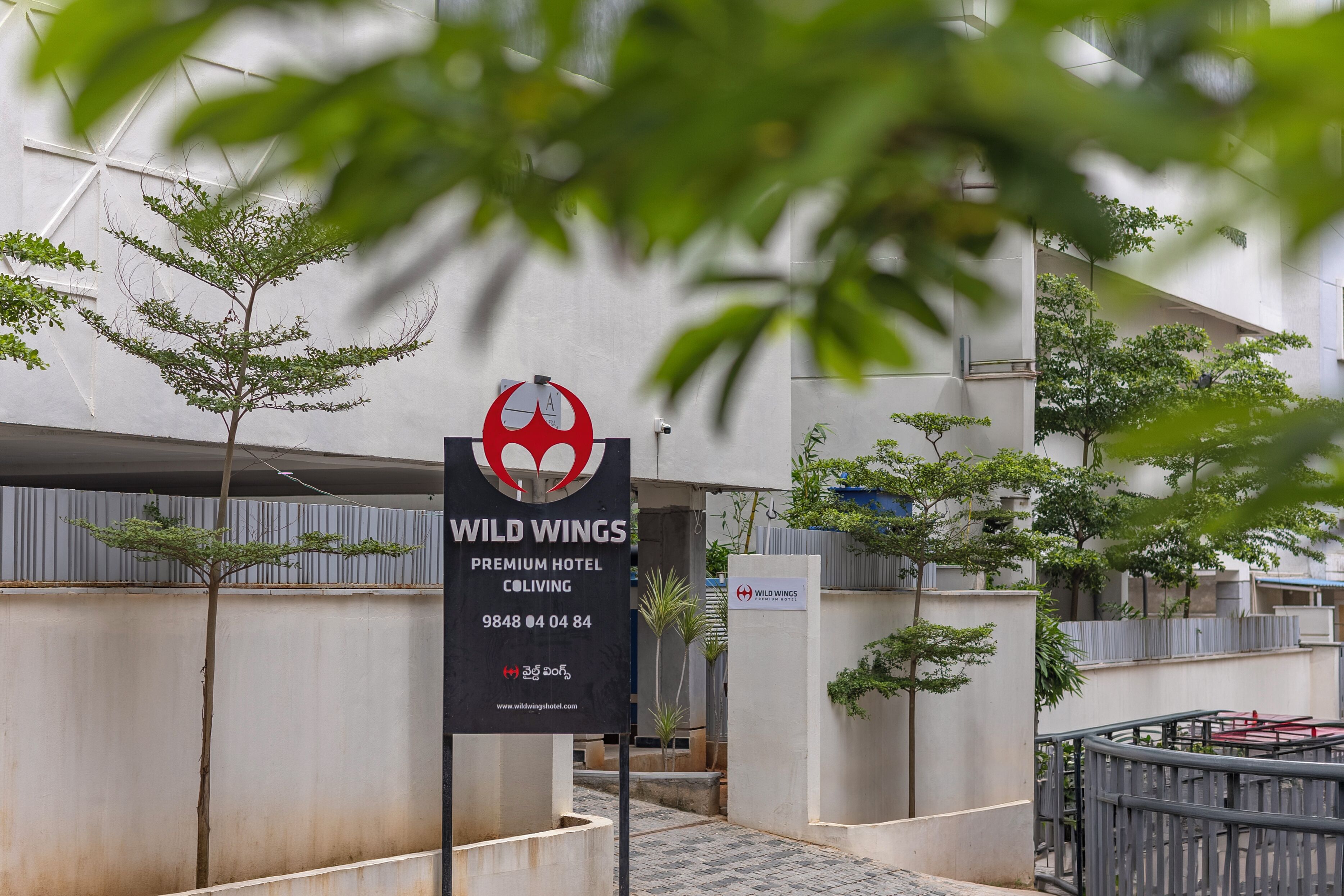 A sign for Wild Wings Premium Hotel Coliving with contact information and a website URL.
