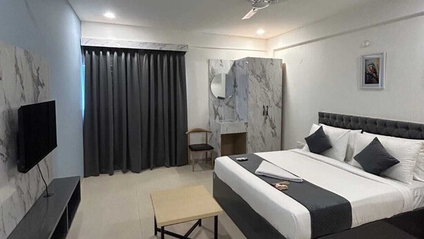 A modern hotel room with a large bed, a flat-screen TV, a small table, and a ceiling fan. - WILDWINGS PREMIUM HOTEL (Hyderabad)