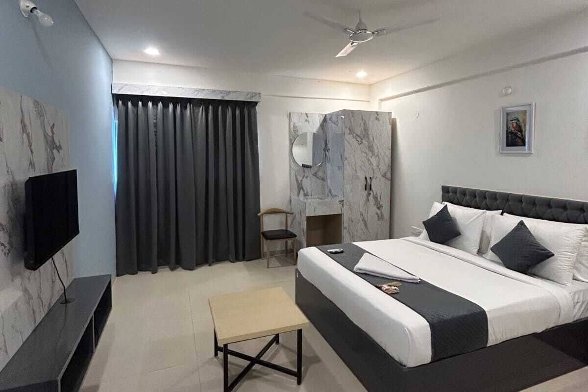 Een moderne hotelkamer met een groot bed, een flatscreen televisie, een klein tafeltje en een plafondventilator.