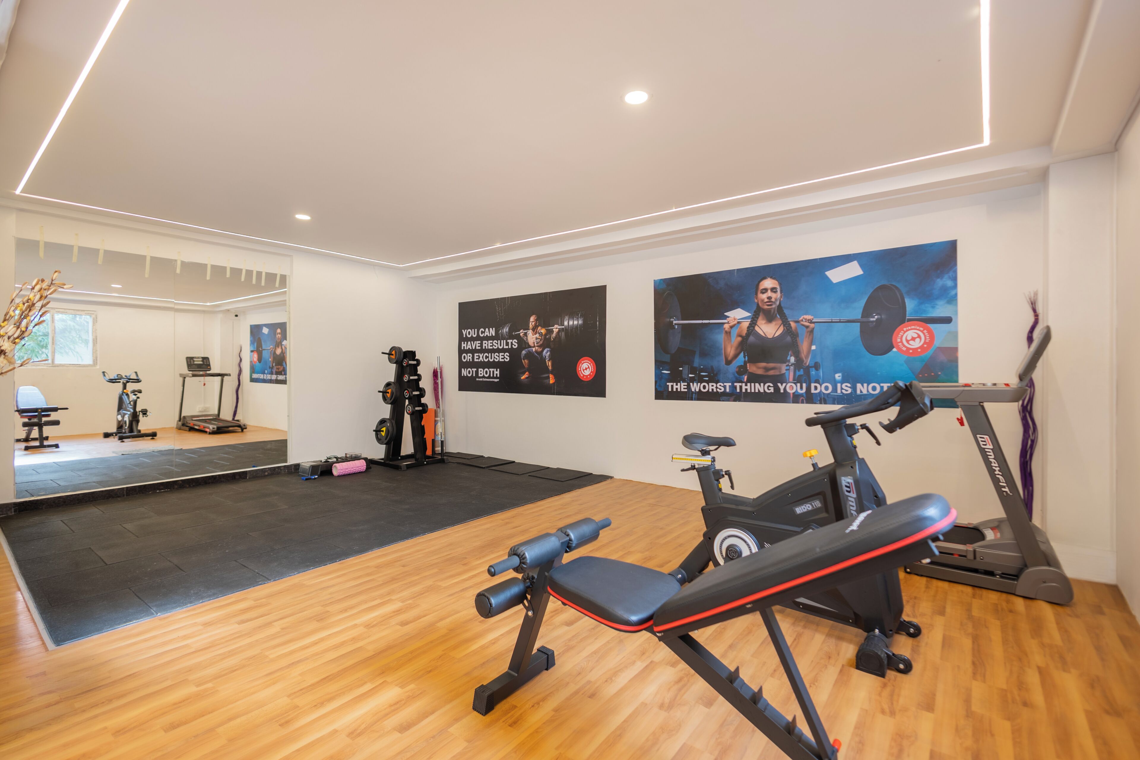 Ein Fitnessraum mit Trainingsgeräten, einem Spiegel und motivierenden Postern.