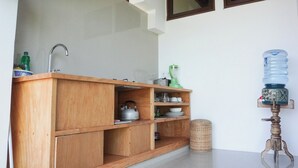 A wooden kitchen counter with a kettle, a water dispenser, and various kitchen items. - Anda Amed Villa and Spa (Karangasem)
