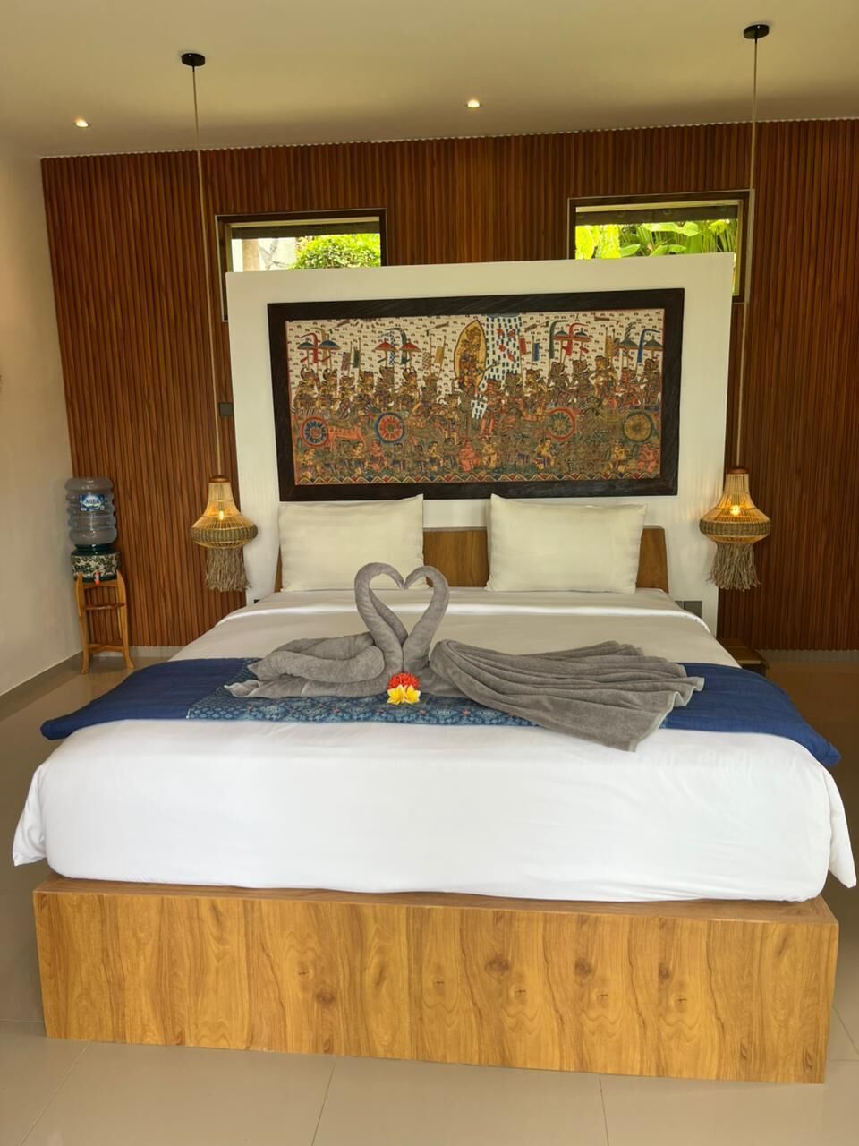 A hotel room with a large bed, wooden headboard, and a decorative tapestry.