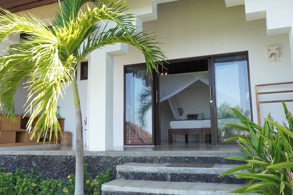 Uma villa moderna com porta de entrada de vidro, escadaria de pedra e vista para o interior.