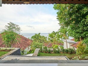 Una propiedad costera con vista al mar, que cuenta con un jardín con diversas plantas y un tejado de tejas.