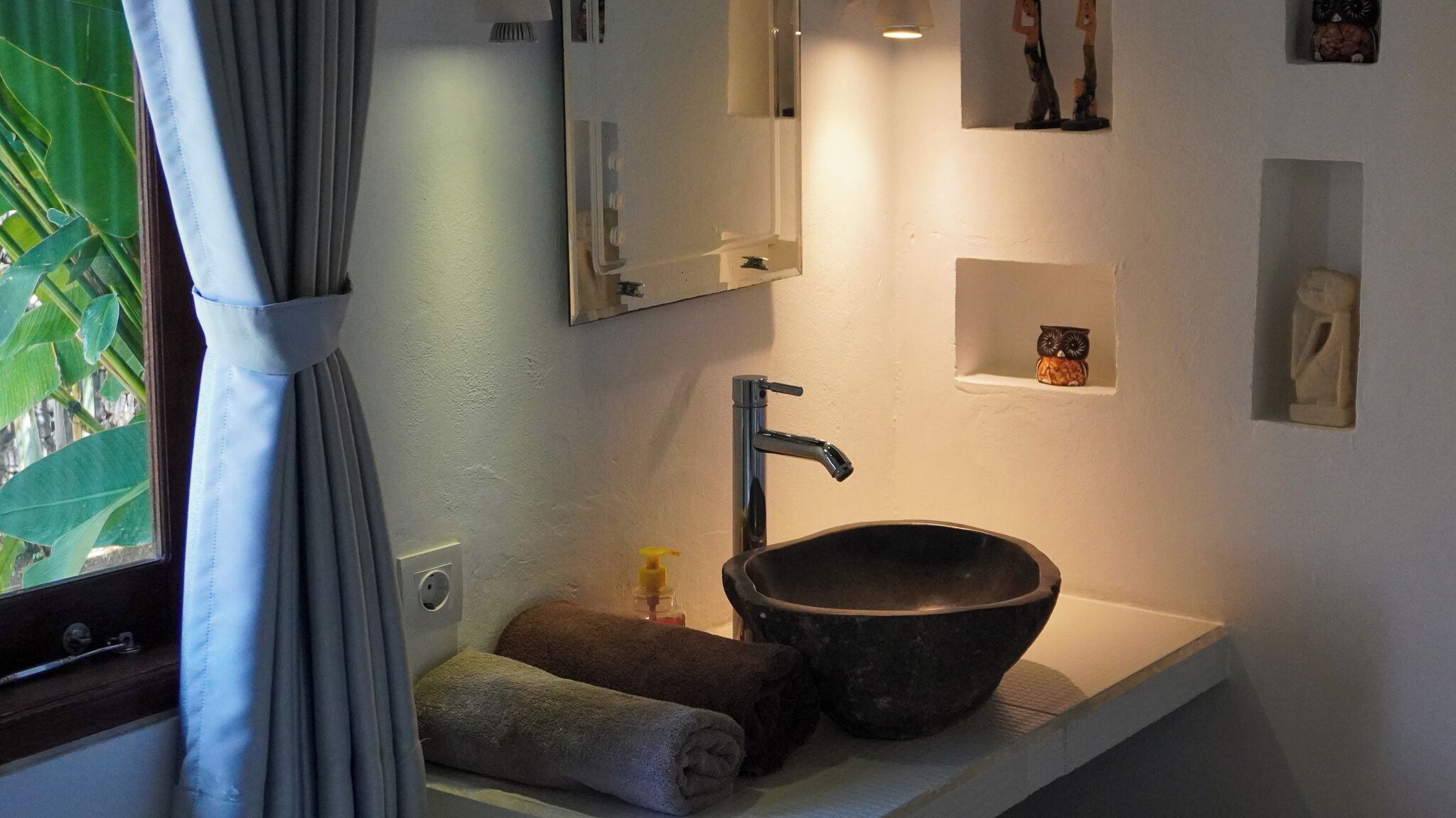A bathroom with a large bowl sink, a mirror, and a towel on the counter.