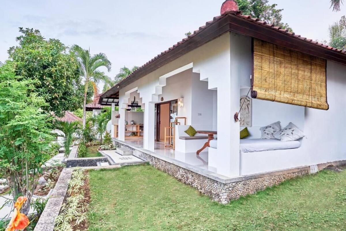 Uma casa moderna com varanda coberta, um pequeno jardim e uma escadaria que leva à entrada.
