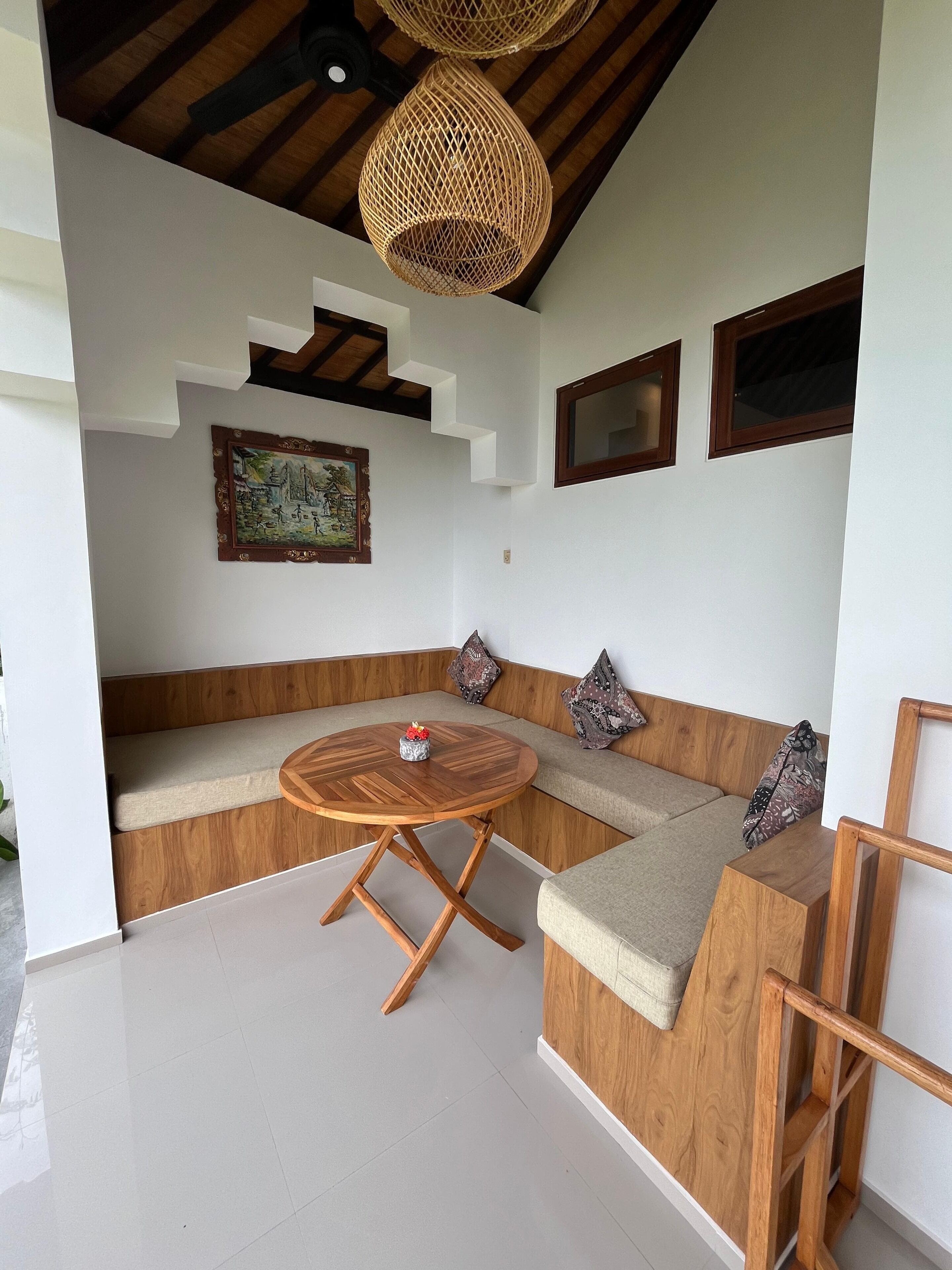 A modern interior with a wooden bench, a round table, and a ceiling with woven light fixtures.