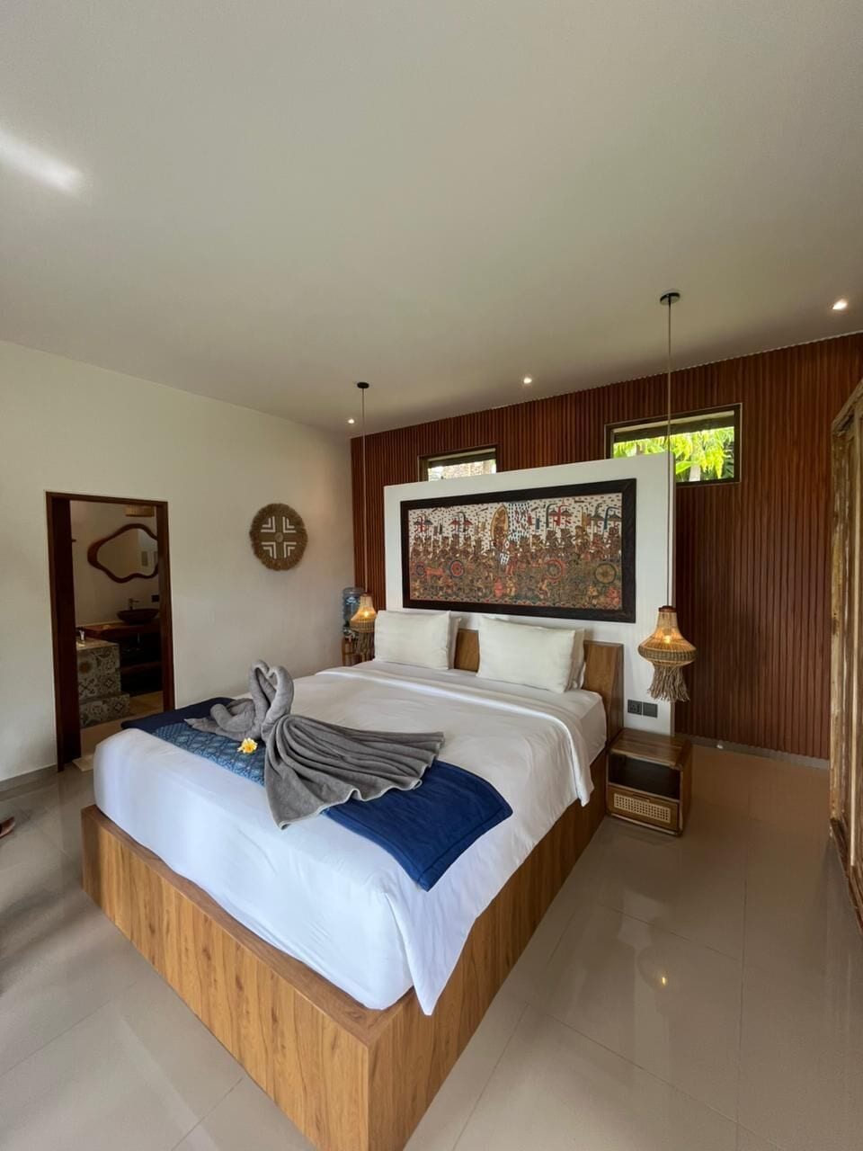 Un dormitorio moderno con una cama grande, una obra de arte en la pared y un cabecero de madera.
