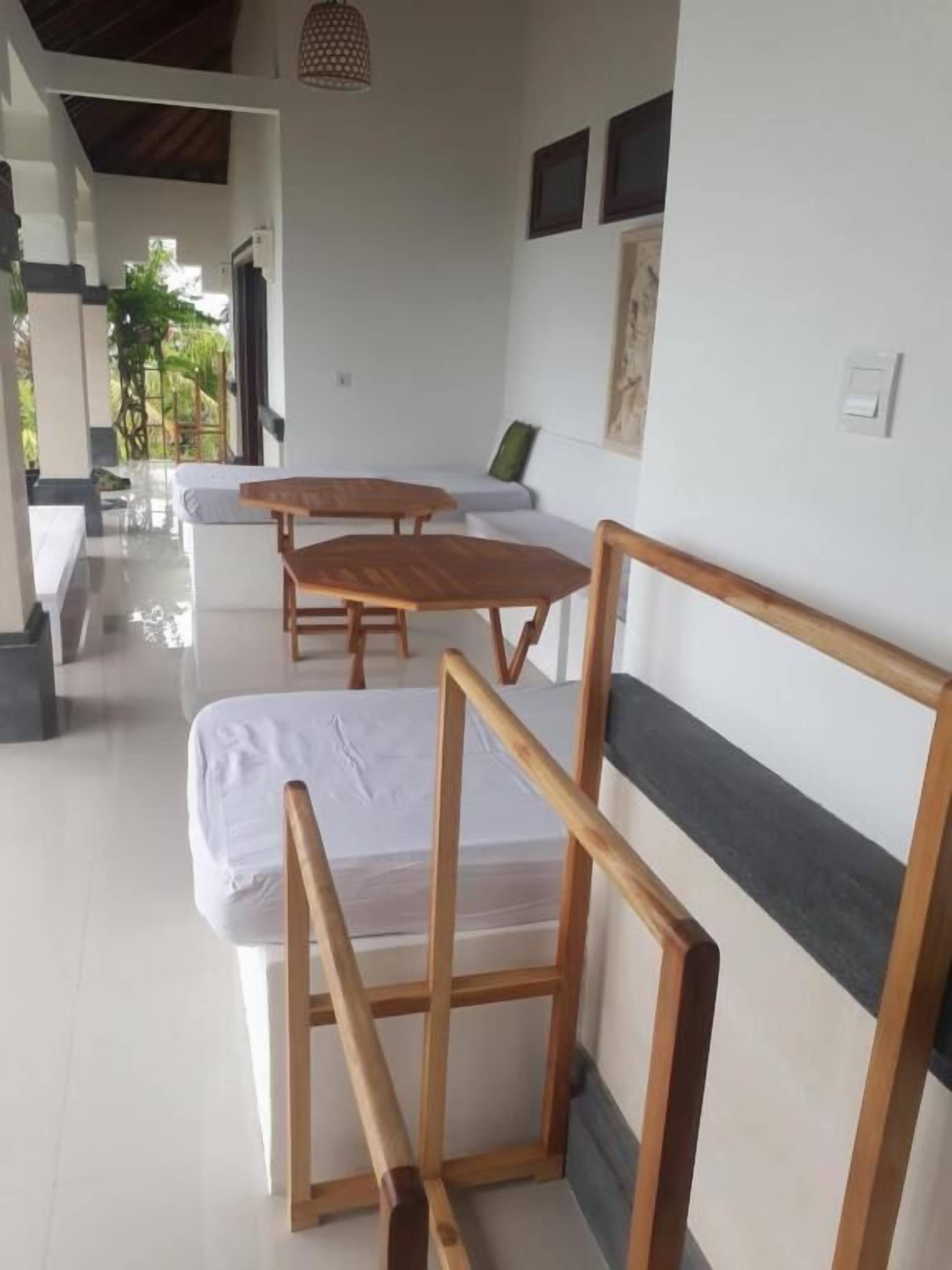 Una habitación con una cama, una silla de madera, una mesita y un sofá.