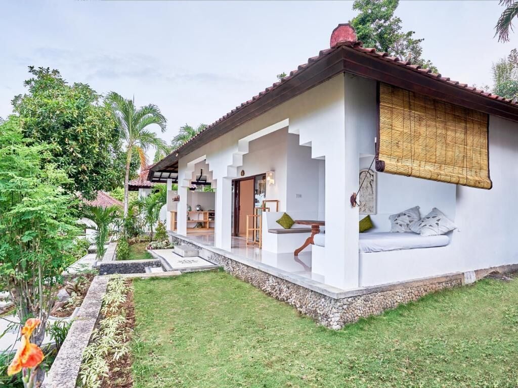 A modern house with a covered porch, a small garden, and a staircase leading to the entrance.