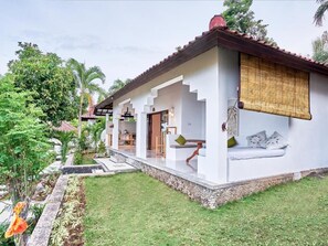 Una casa moderna con un porche cubierto, un pequeño jardín y una escalera que conduce a la entrada.