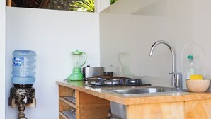A compact kitchen with a sink, a water dispenser, a blender, and a small wooden bowl. - Anda Amed Villa and Spa (Karangasem)