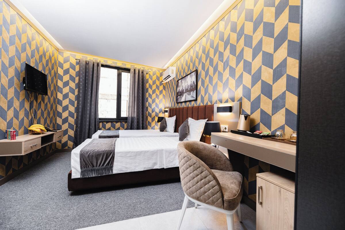 Una habitación de hotel con una cama grande, un escritorio, una silla y un televisor en la pared.