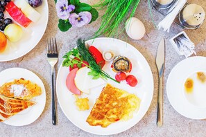A breakfast setting with plates of food, utensils, and decorative flowers. - Art Air Hotel (Tashkent)