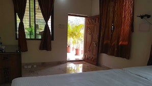 Un dormitorio con cama, armario de madera, ventana con cortinas y vistas al exterior.