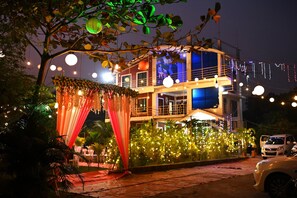 A multi-story building with a balcony and string lights. - Krushnakunj Holiday Resort, Nagaon (Alibag)