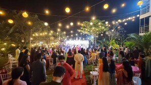 Evento al aire libre con luces colgantes y un escenario.
