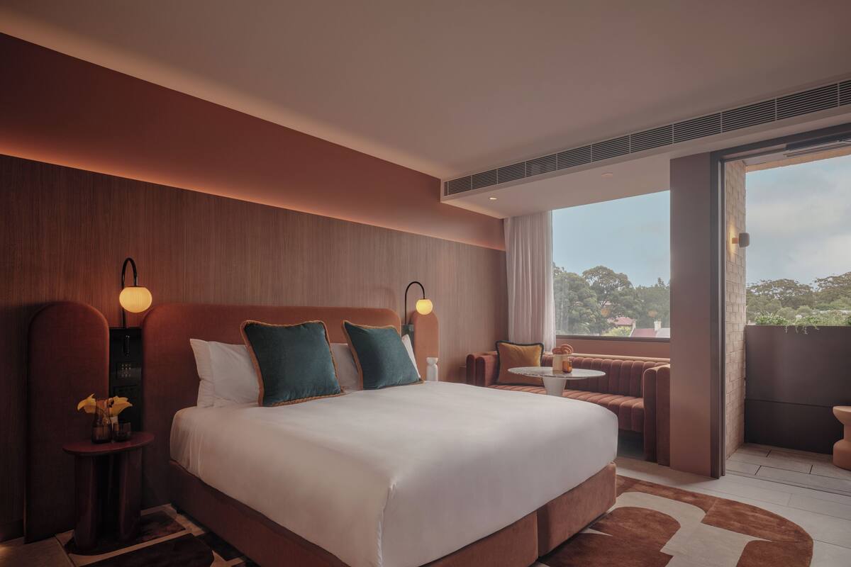 Ein modernes Hotelzimmer mit einem großen Bett, einem kleinen Tisch und Blick ins Freie.