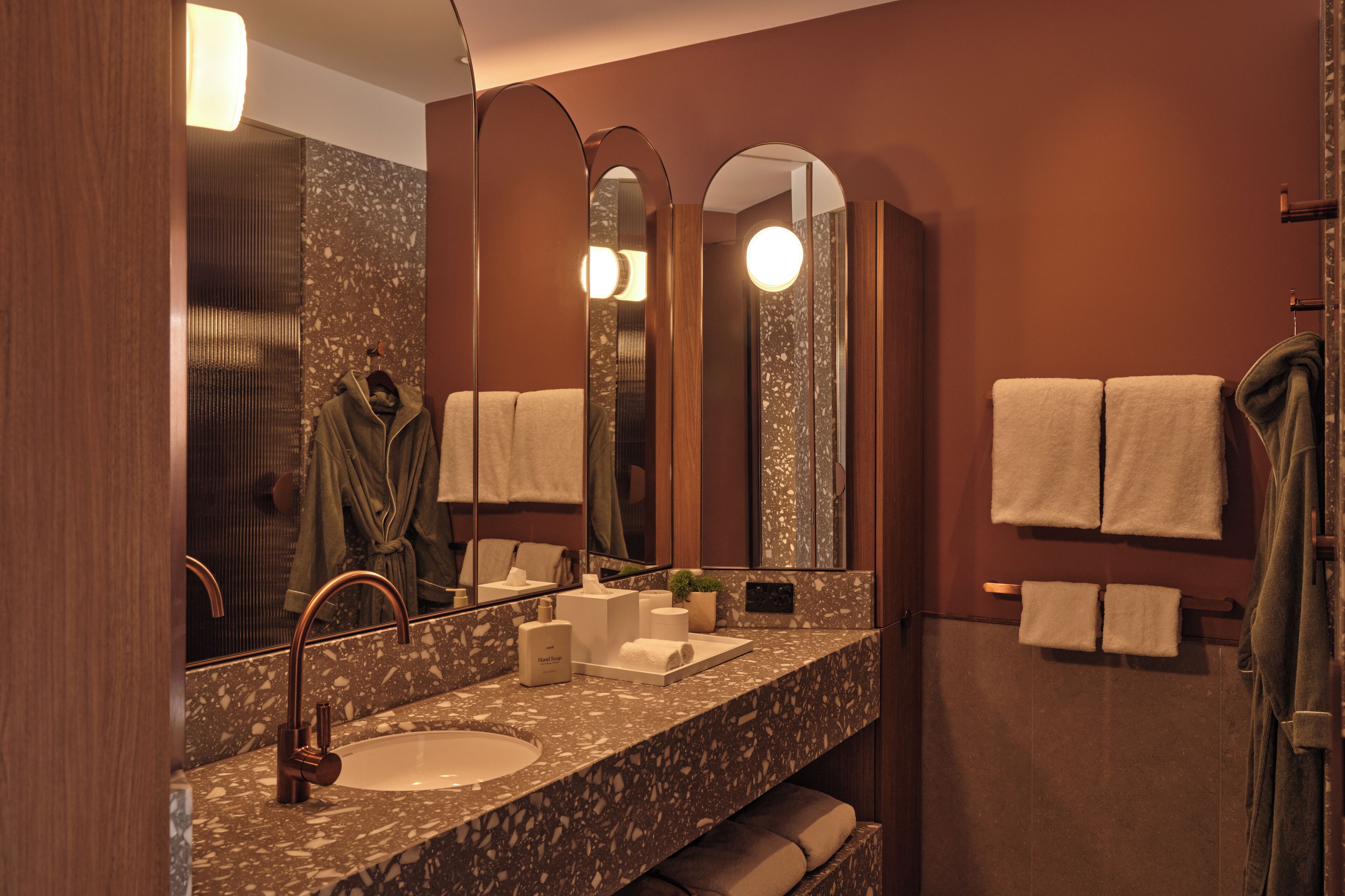 A modern bathroom with a granite countertop, a sink, a mirror, and two towel racks.