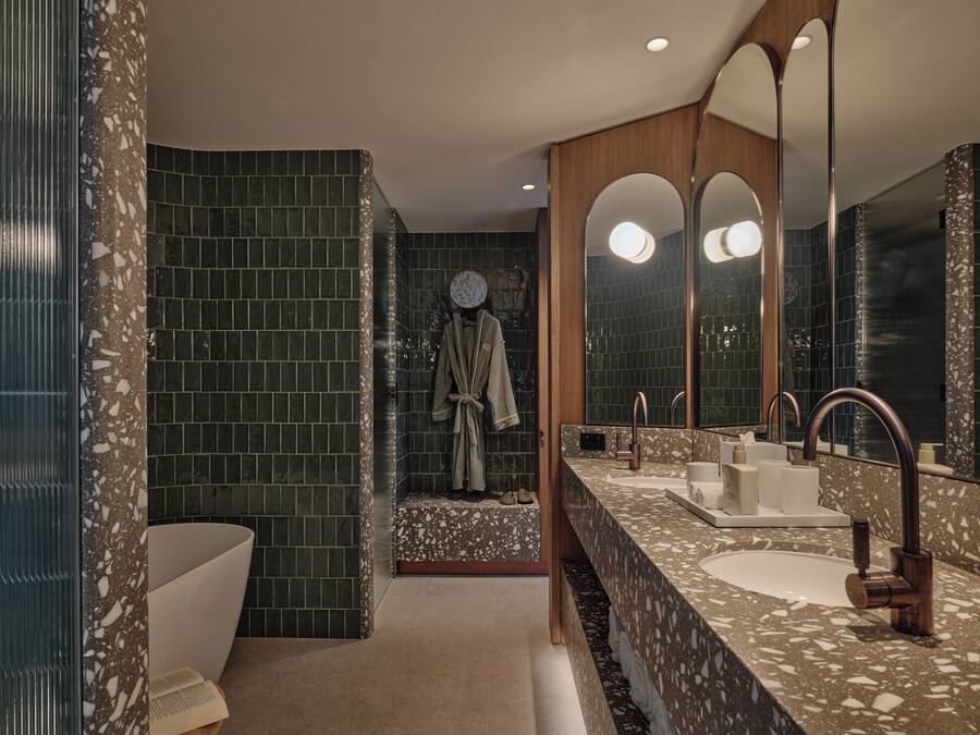 Un baño moderno con un espejo grande, dos lavamanos y una bañera.