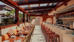 A restaurant with a long counter, multiple tables, and bar seating. - The EVE Hotel Sydney (Redfern)