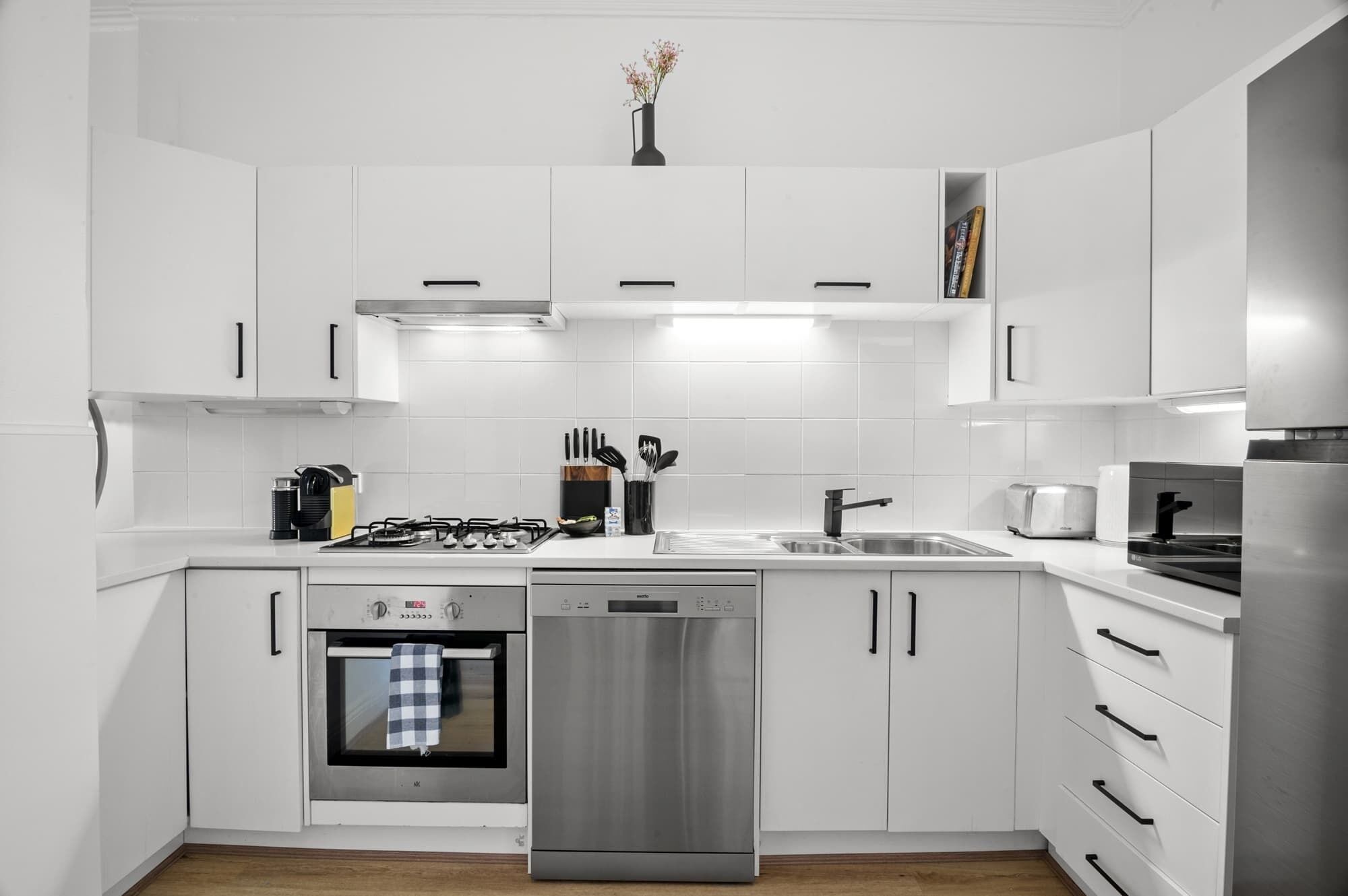 A modern kitchen with white cabinets, stainless steel appliances, and a central island.