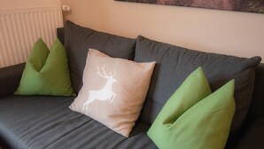 A grey sofa with three cushions, one with a deer design and two green ones. - Hochkönig 4 Apartment (Embach)