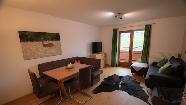Una sala de estar con una mesa de madera, dos sofás, un televisor y un cuadro grande de un ciervo.