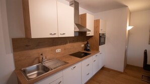 Una cocina moderna con armarios blancos, encimera de madera, pileta de acero inoxidable y horno empotrado.