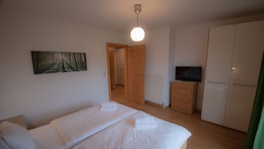 Un dormitorio con dos camas, un armario de madera, un televisor y un radiador.